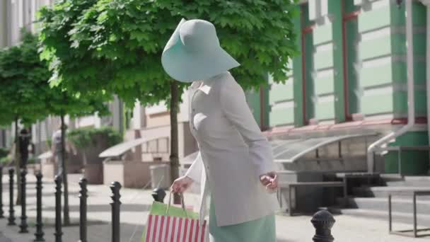 Retrato de una elegante mujer caucásica perdida en una ciudad extranjera. Mujer con estilo incierto con bolsas de compras mirando a su alrededor decidiendo la ruta a seguir. Turismo, viajes, ocio, elegancia . — Vídeo de stock