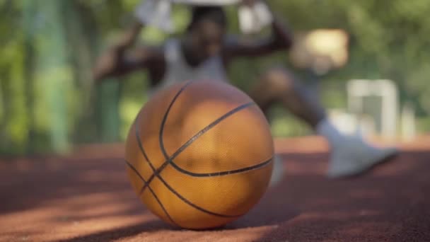 Suddig afroamerikansk idrottsman tar bollen på framsidan och lämnar. Ung sportig man spelar basket på friluftsplan på solig dag. Livsstil, tävlingssport, träning. — Stockvideo