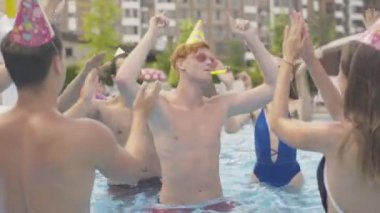 Genç kızıl saçlı adam doğum gününü bilardoda arkadaşlarıyla kutluyor. Etrafta neşeli insanlarla tatil köyünde dans eden mutlu beyaz adamın portresi. Dışarıda yaz günü komik bir parti var..