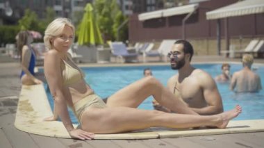 Kendinden emin Orta Doğulu bir adam kokteyl gözlüklü, sarışın, beyaz bir kadına geliyor. Yakışıklı sporcu erkek turistin portresi tatil köyünde güzel, ince bir bayana çıkma teklif ediyor. Çıkma, romantizm.