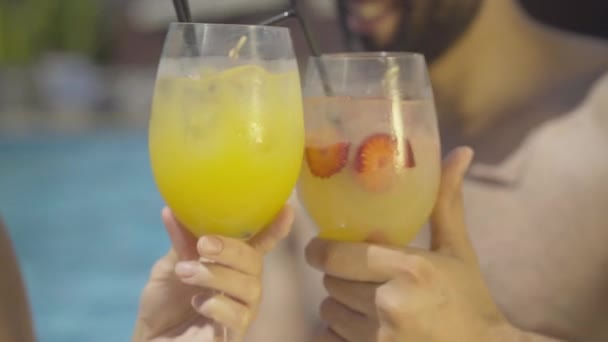 Mains masculines et féminines cliquetis verres à cocktail. Gros plan d'un homme et d'une femme méconnaissables buvant de l'alcool dans un complexe luxueux situé dans une piscine d'eau extérieure. — Video