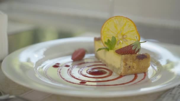 Primer plano de delicioso pastel con rodaja de naranja y fresa en plato blanco en el restaurante. Sabroso postre dulce panadería en la cafetería. Gastronomía, cocina . — Vídeos de Stock