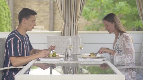Портрет щасливих туристів, які їдять делікатес у ресторані і розмовляють. Молоді кавказькі чоловіки і жінки відпочивають у кафе в сонячний літній день і базікають. Розкішний туризм. — стокове відео
