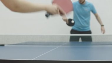 Tanımlanamayan Kafkasyalı sporcu kadın, bulanık sporcuyla pinpon oynuyor. Spor salonunda masa tenisi oynayan iki yetişkin beyaz adam. Spor konsepti.