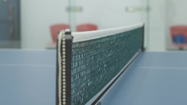 Nærbillede af bordtennisnet med bordtennisbold. Ukendte mennesker spiller sport spil i gymnastiksalen indendørs. – Stock-video