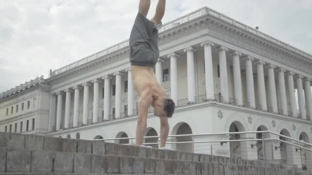 Un'ampia foto di un giovane atletico che scende le scale con le mani. Fiduciosa bruna caucasica break dancer che fa performance d'arte moderna sulla piazza della città. Stile di vita concetto. — Video Stock