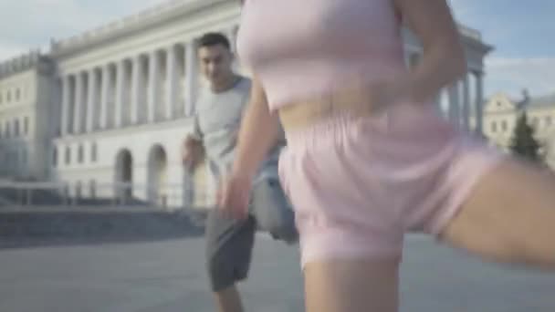 Câmera se move para baixo e para cima ao longo do corpo da linda mulher caucasiana dançando no dia ensolarado de verão com amigos ao ar livre. Grupo de pessoas alegres que se apresentam no centro da cidade . — Vídeo de Stock