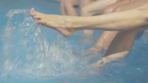 Slim pies caucásicos femeninos salpicaduras de agua en la piscina en el complejo. Mujeres jóvenes irreconocibles descansando en el soleado día de verano al aire libre. Turismo, ocio, relajación, estilo de vida . — Vídeos de Stock