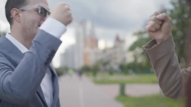 Hombre guapo positivo en gafas de sol saludando a amigos en la calle de la ciudad. Retrato de chico elegante con confianza reunión con los compañeros en el soleado día de verano en el descanso. — Vídeos de Stock