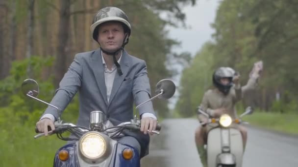 Orang yang percaya diri mengendarai skuter sementara beberapa teman mengendarai video selfie. Portrait of Caucasian bikers having fun outdoors on cloudy summer day. — Stok Video