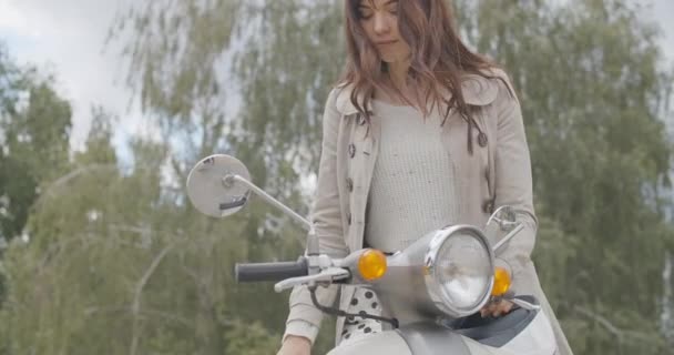 Preciosa mujer positiva caucásica que viene a la motocicleta en el día de verano. Retrato de la hermosa morena motorista sentada en scooter y sonriendo. A cámara lenta, lento. Sede del cine 4k ProRes. — Vídeo de stock