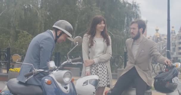 三个无忧无虑的人在雨和笑声中聊天.白人男子和妇女坐在摩托车上，在夏日雨天聊天的画像。慢动作Cinema 4k ProRes HQ. — 图库视频影像