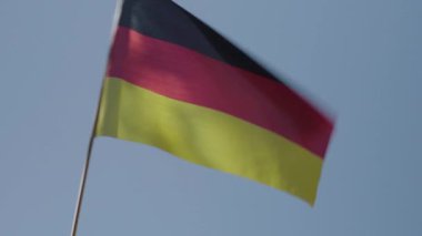 Açık mavi gökyüzünün arka planında dalgalanan Alman bayrağı. Güneşli yaz ya da sonbahar günlerinde Almanya 'nın ulusal sembolü. Vatanseverlik ve etnik köken kavramı.