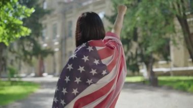 Amerikan bayrağında el hareketi yapan esmer bir kadın. Üniversite bahçesinde özgürlük işareti gösteren sıska bir bayan. Bağımsızlık kavramı veya protesto.