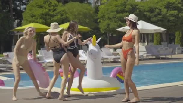 Широкий снимок веселых женщин, танцующих у бассейна на курорте. Портрет счастливых взрослых кавказских туристов, наслаждающихся солнечным летним днем на открытом воздухе. Четыре веселые дамы отдыхают в отпуске. — стоковое видео