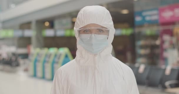 Komoly kaukázusi nő portréja védőruhában, aki érintésmentes hőmérőt mutat a kamerára és a nyomógombra. A reptéri bejáratnál végzett átvizsgálás utasnyilvántartása. Cinema 4k ProRes főhadiszállás. — Stock videók