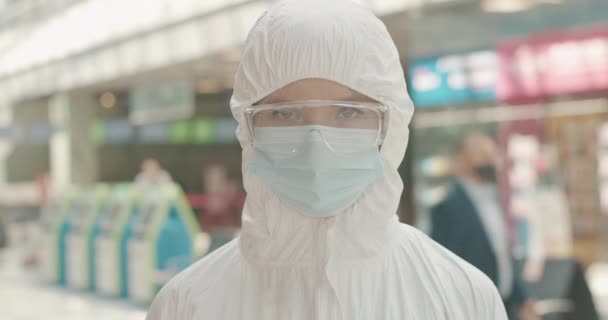 Grave dipendente aeroporto femminile in occhiali e maschera che mostra gesto di arresto. Focus rack cambia da donne faccia a faccia in guanti protettivi. Covid-19 restrizioni turistiche. Cinema 4k ProRes HQ. — Video Stock