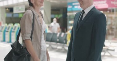 Havaalanında, tren istasyonunda ya da otobüs durağında konuşan ve gülen tanınmamış orta yaşlı kadın ve erkek. İki Kafkasyalı turist seyahatte buluşuyor. Turizm ve seyahat konsepti. Sinema 4k ProRes Merkezi.