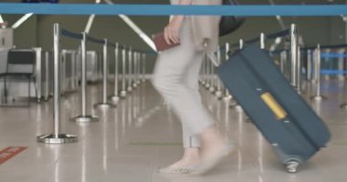 Erkek ve kadın bacakları kalkış terminalinde havaalanı koridorunda bavulla yürüyor. Tanımlanamayan turistler bagajlarıyla gemiye biniyorlar. Turizm ve seyahat. Sinema 4k ProRes Merkezi.