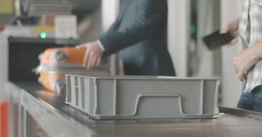 Tanımlanamayan bir adam ve kadın bagajlarını tarayıcıya koyup havaalanındaki güvenlik kapılarından geçiyorlar. Turistler uçağa binmek için uçağa biniyorlar. Uluslararası hava yolculuğu. Sinema 4k ProRes Merkezi.