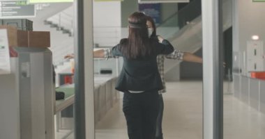 Havaalanı kontrol noktasında kadın turistin fiziksel muayenesi. Çalışan, çıkış kapılarında yüz maskesi takan beyaz bir kadını kontrol ediyor. Covid-19 karantinaya alınıyor. Sinema 4k ProRes Merkezi.
