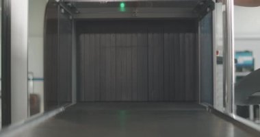 Havaalanı tarayıcısından çıkan turuncu bavul ve bagajı alan tanınmayan bir adam. Uluslararası kalkış terminalinde kontrol noktası. Yolculuk için erkek turist. Turizm. Sinema 4k ProRes Merkezi.