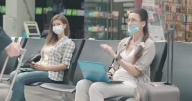 Bilinci açık kadın turist, oturmayı reddediyor. Covid-19 'dan sosyal mesafeyi koruyarak havalimanında kalkmayı bekleyen maskeli, kendinden emin, orta yaşlı beyaz kadın portresi. Sinema 4k ProRes Merkezi.