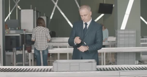 Portrait d'un homme d'affaires caucasien adulte confiant passant un contrôle de sécurité à l'aéroport. L'homme en costume officiel met des bagages dans le scanner et part. Tourisme international. Siège social de Cinema 4k proRes. — Video