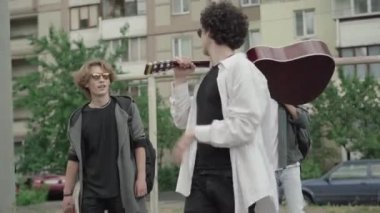 1980 'lerin ya da 1990' ların arkadaşlarının açık havada sırt çantaları, gitarları ve konuşmalarla dolaştıkları portreler. Şehir avlusunda gezinen üç etnik çeşitlilikte genç adam. Retro tarzı, erkek arkadaşlığı..