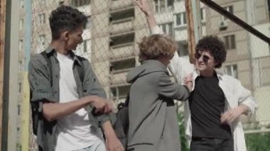 Üç mutlu erkek arkadaş çitin önünde dikilip konuşuyorlar. 1980 'lerde gülümseyen beyaz ve Afro-Amerikan erkekler açık havada sohbet ediyorlardı. Açık havada neşeli lise öğrencilerinin portresi..