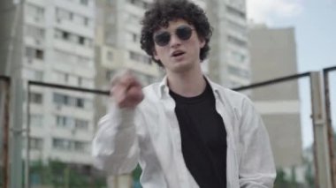 Güneş gözlüklü genç, kıvırcık saçlı beyaz adamın portresi rap söylüyor ve şehir merkezine taşınıyor. Gülümseyen neşeli rapçi 1980 'lerde ya da 1990' larda şehirde sahne aldı. Retro müzikal yaşam tarzı.