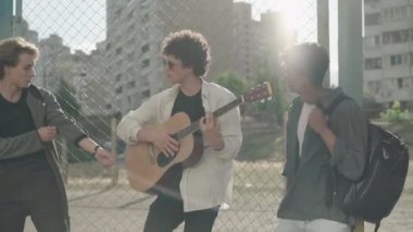 Günbatımında gitar çalan ve açık havada şarkı söyleyen 1980 'lerin ya da 1990' ların gruplarının portresi. Farklı etnik kökenlere sahip üç kendine güvenen adam şehir şehrinde müziğin keyfini çıkarıyor. Mutlu müzisyenler gün ışığında gösteri yapıyorlar..