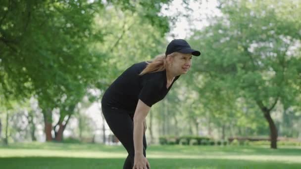屋外でのトレーニングに膝の痛みを持つ中大人のスポーツ女性の肖像画。スポーツウェアをこすり足で積極的な白人女性。晴れた夏の公園に立つ女性ランナーやジョギング. — ストック動画