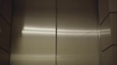 Asansör kapısı açılır ve utangaç genç bir kadın dışarı çıkar. Güzel esmer, beyaz tenli bir çalışanın portresi. Belge klasörüyle birlikte ayrılıyor. İş ve istihdam kavramı.