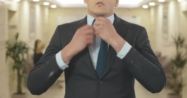 Unerkennbarer junger Geschäftsmann verliert Krawatte und Anzugknöpfe. Müde gestresste Kaukasier seufzen, als sie im Business Center Hall im Büro stehen. Cinema 4k ProRes Hauptquartier. — Stockvideo