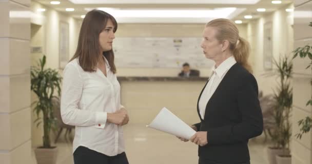 หญิงสาวผิวสีน้ําตาลผิวขาวพูดคุยกับพนักงานวัยกลางคนอย่างจริงจัง รูปภาพของซีอีโอหญิงที่มีความมั่นใจคนงานกบฏในศูนย์ธุรกิจฮอลล์ แนวคิดการจัดการความขัดแย้ง โรงภาพยนตร์ 4k ProRes HQ . — วีดีโอสต็อก