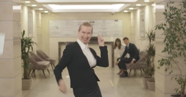 事務所で踊っている幸せな中年のビジネスマンが書類を投げ捨てる。ビジネスセンターで成功を収めている正の白人女性。黒人の仲間が踊りに参加した。シネマ4k｜ProRes HQ. — ストック動画