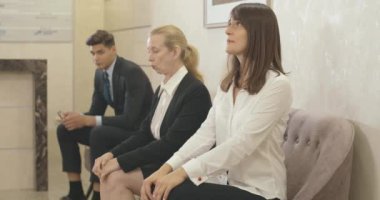 Tedirgin genç bir kadının umut jesti yaptığını görüyorum. Beyaz tenli başvuru sahibi iş merkezinin ofisindeki yarışmacılarla iş görüşmesi için bekliyor. İK konsepti. Sinema 4k ProRes Merkezi.