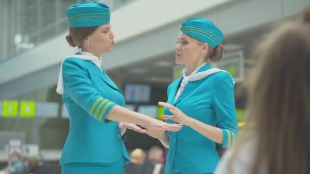 两个信心十足的空姐在机场交谈，就像一个模模糊糊的小女孩在前面欣赏他们一样。难以辨认的黑发小孩梦想着将来当空姐.国际旅游业. — 图库视频影像