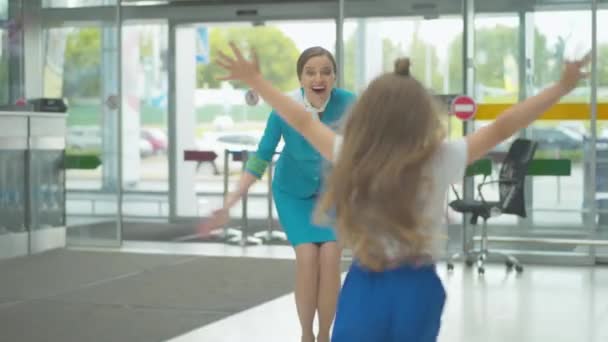 Cheerful little girl meeting mother stewardess in airport. Back view of happy Caucasian child running to smiling parent and hugging mom. Slim beautiful flight attendant returning to daughter. — Stock Video