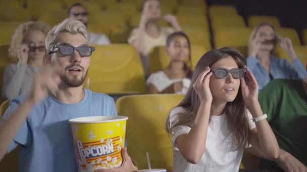 3d 안경을 쓰고 영화를 보는 사람들이 있습니다. 근심없는 다종 민족 남성과 여성이 코미디 영화를 즐기고 웃는 모습. 긴장 한 청중은 팝콘을 먹고 웃는다. — 비디오