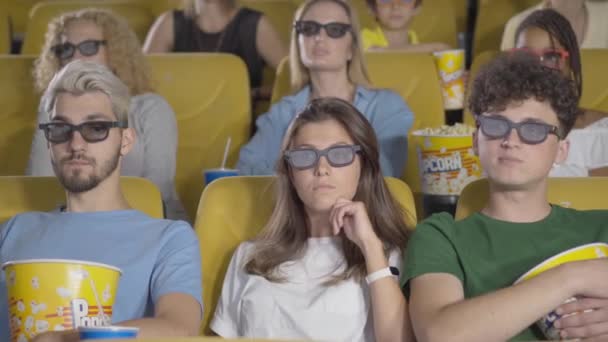 Visitantes de cine concentrados en gafas 3D viendo películas y comiendo palomitas de maíz. Grupo de personas disfrutando de la cinematografía en el cine. Amantes del cine descansando los fines de semana. — Vídeo de stock