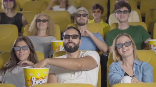 Público multiétnico positivo riendo, quitándose las gafas 3D y dejando el cine. Retrato de felices hombres y mujeres satisfechos disfrutando del cine en el cine. Personas despreocupadas descansando los fines de semana. — Vídeo de stock