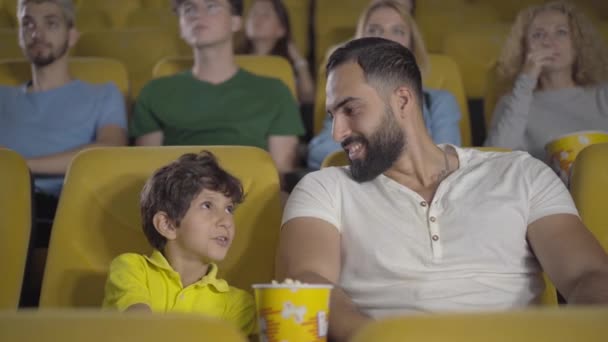 影片中中东父亲闭上儿子眼睛看着不适当场景的肖像。快乐的父母和孩子在电影院看电影.父母与童年概念、家庭休闲. — 图库视频影像