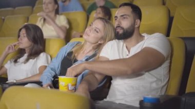 Sinemada film izleyen ve patlamış mısır yiyen genç, çok ırklı bir çift. Orta Doğulu yakışıklı bir adam ve sinemada çıkan güzel beyaz bir kadının açısı..