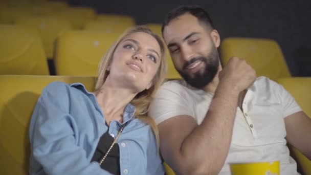 Amar casal multiétnico assistindo filme no cinema. Retrato de homem feliz do Oriente Médio e mulher caucasiana desfrutando de encontro no cinema. Namoro, amor, unidade e conceito de ligação. — Vídeo de Stock