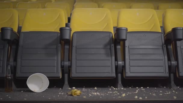 Die Kamera bewegt sich im dreckigen leeren Kino mit gelben Stühlen. Kino mit Popcorn und Bananenschalen auf dem Boden. Kinosaal nach Besuchern. — Stockvideo