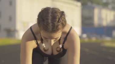 Kendine güvenen konsantre sporcu kadının yüzünü yukarı kaldırıp koşmaya başlaması. Güneşli bir sabahta açık havada antrenman yapan güzel, zayıf, beyaz bir kadın. Güneş doğarken koşan sportif kadın portresi.