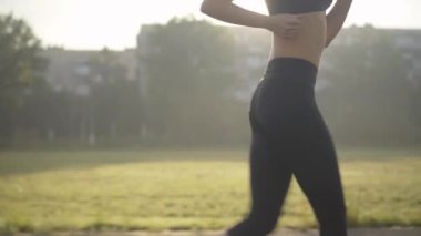 Güneş ışınlarıyla dışarıda koşan tanınmayan sporcu kadının yan görüntüsü. Yaz sabahı güneş ışığında koşan zayıf, sportif, beyaz bir kadın. Güneş doğarken atletik bayan koşucu eğitimi.
