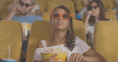 Afro örgülü konsantre Afro-Amerikan kız sinemada patlamış mısırla oturup korku filmi izliyor. Sinemada özümsenmiş bir çocuğun portresi. Sinema 4k ProRes Merkezi.
